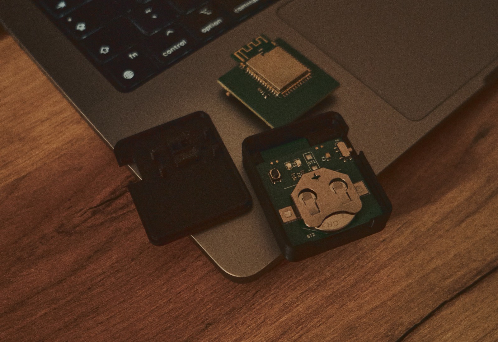 MeetHead opened up: the Bluetooth radio module, the circuit board with a CR2032 coin cell, and the 3D-printed case halves on a desk next to a laptop